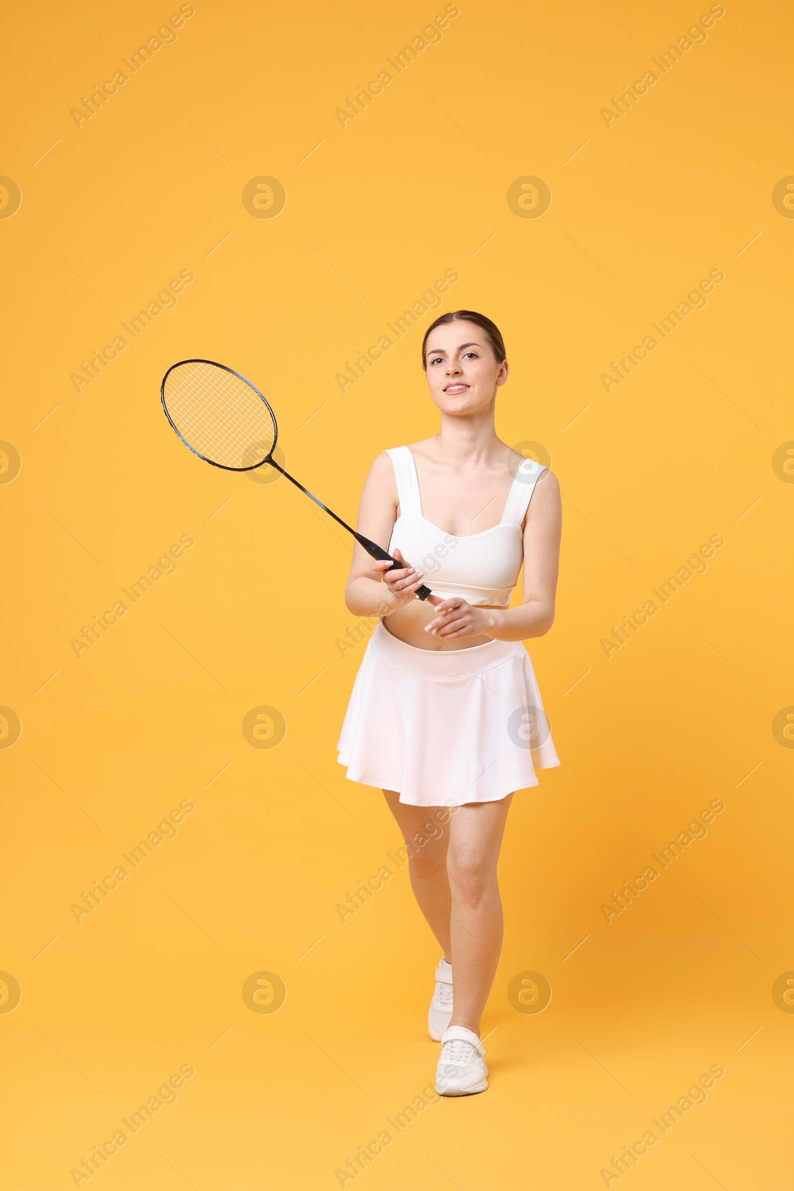 Photo of Young woman with badminton racket on orange background