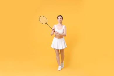 Photo of Young woman with badminton racket on orange background