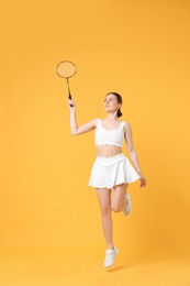 Photo of Young woman with badminton racket on orange background