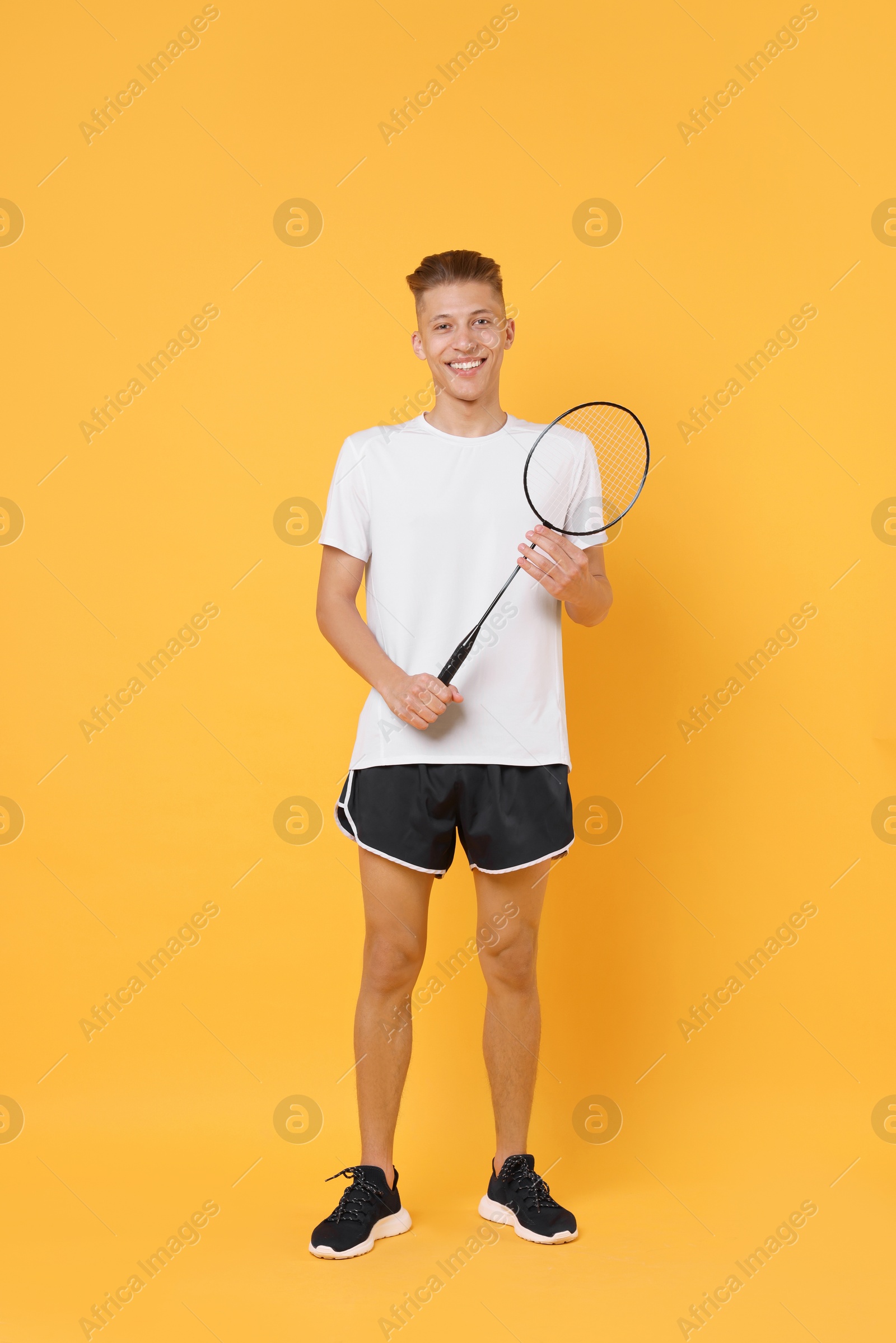 Photo of Young man with badminton racket on orange background