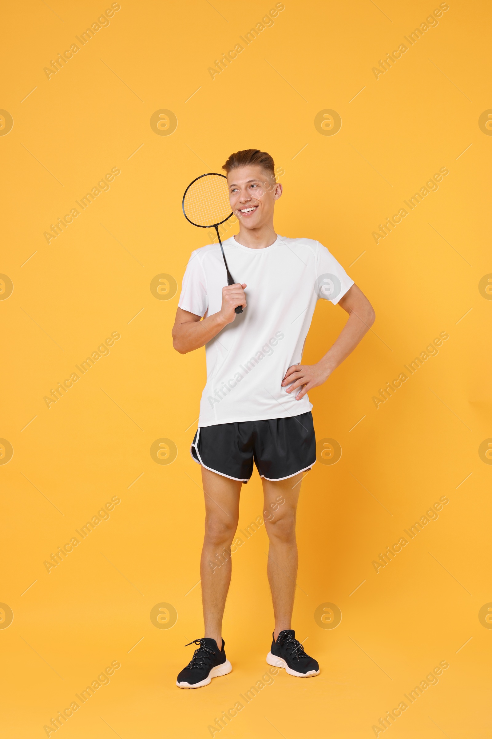 Photo of Young man with badminton racket on orange background