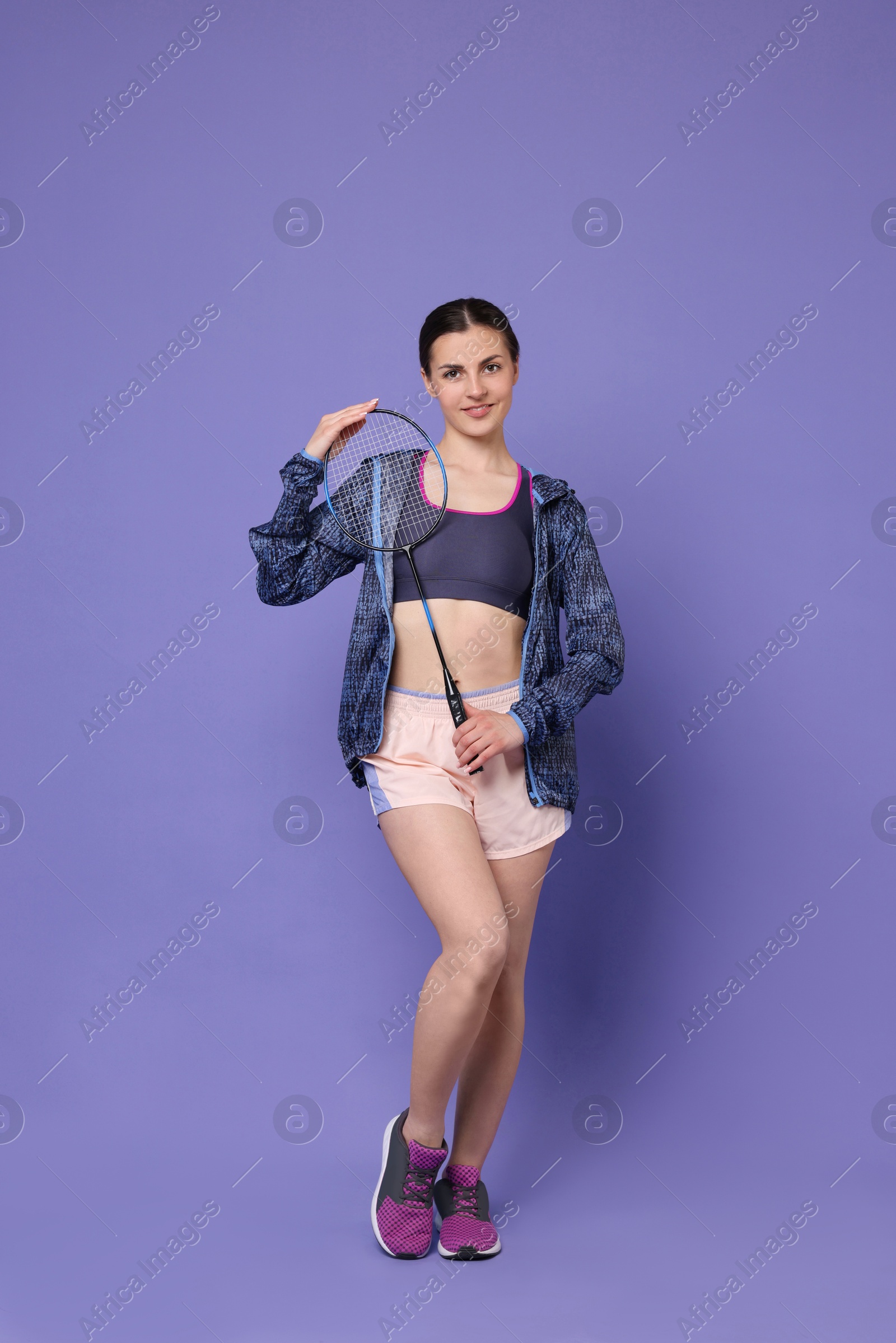 Photo of Young woman with badminton racket on purple background