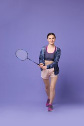 Young woman with badminton racket on purple background