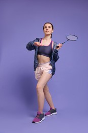 Photo of Young woman playing badminton with racket on purple background