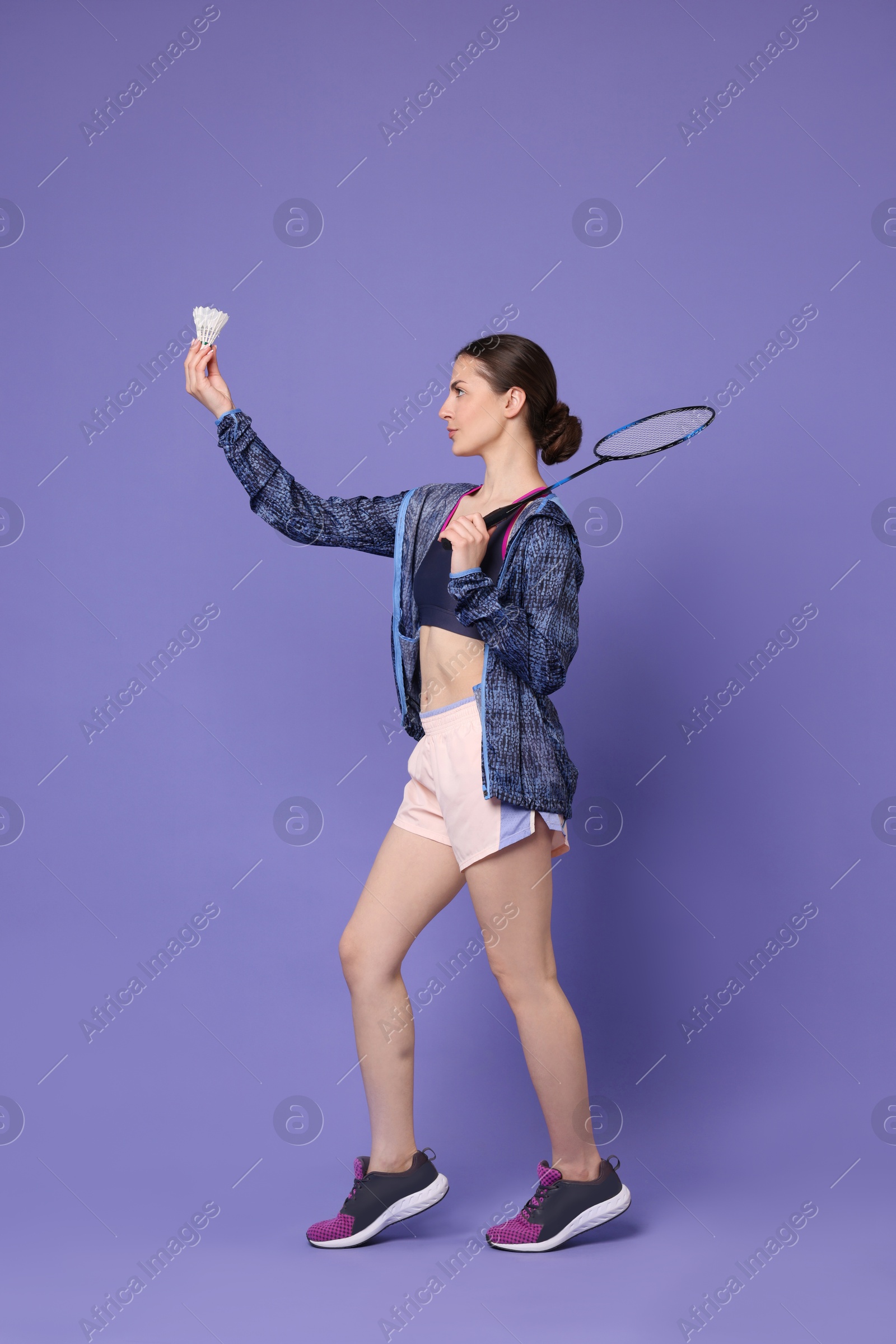 Photo of Young woman with badminton racket and shuttlecock on purple background