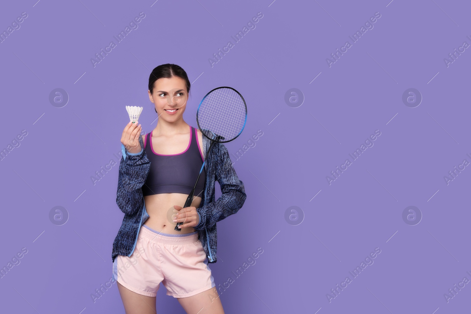 Photo of Young woman with badminton racket and shuttlecock on purple background, space for text