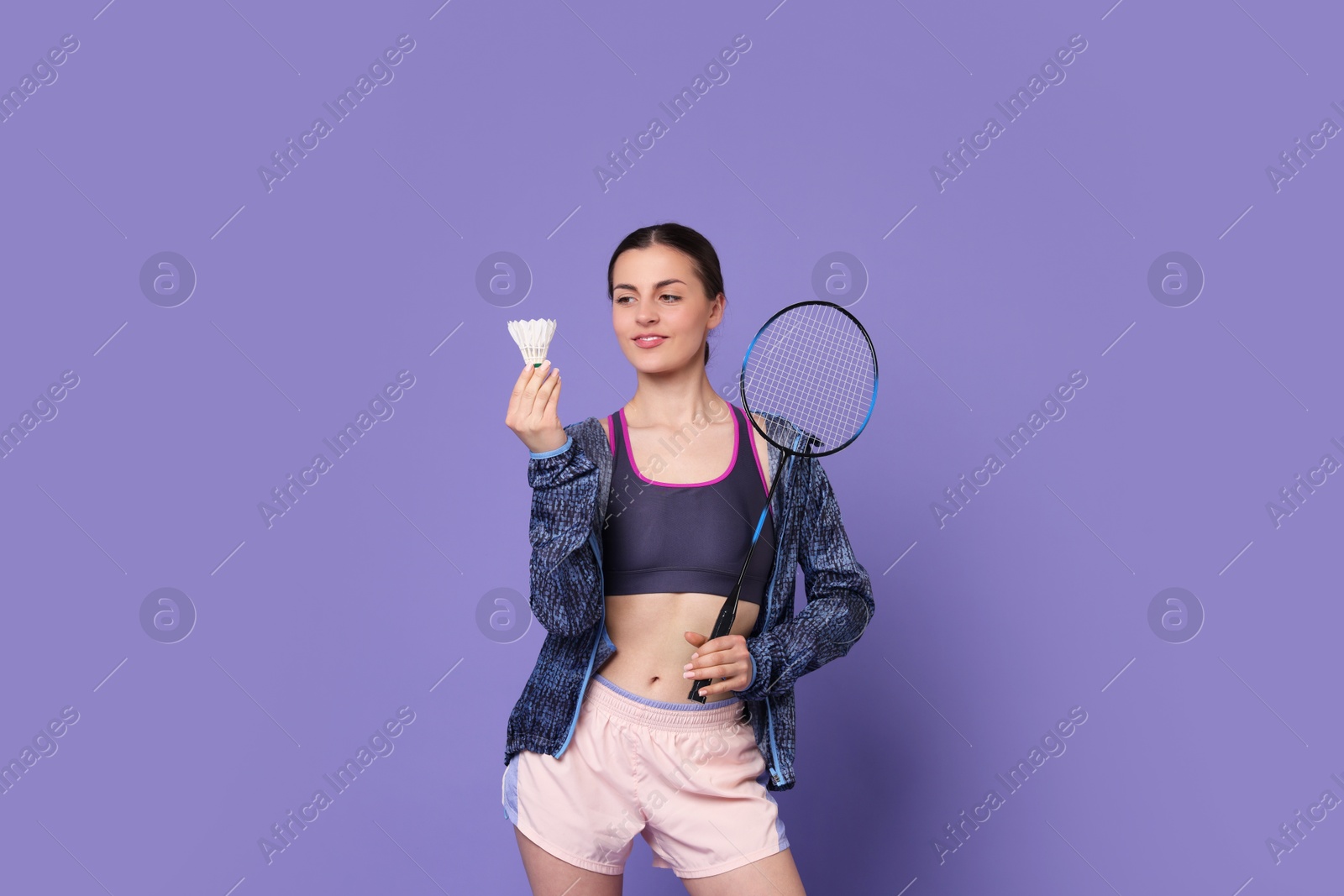 Photo of Young woman with badminton racket and shuttlecock on purple background