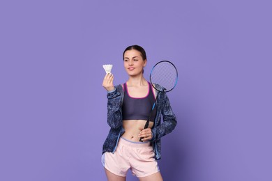 Young woman with badminton racket and shuttlecock on purple background