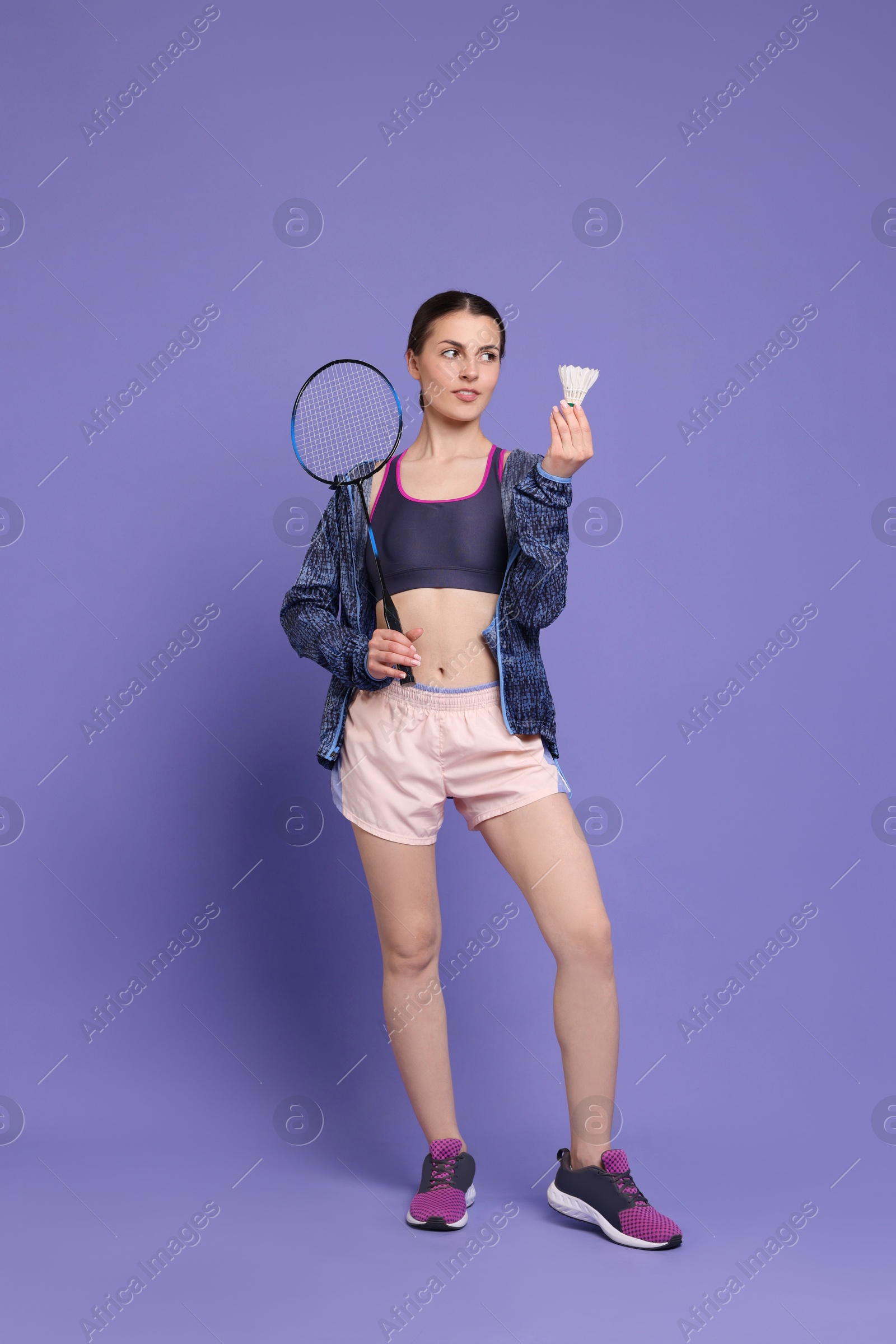 Photo of Young woman with badminton racket and shuttlecock on purple background