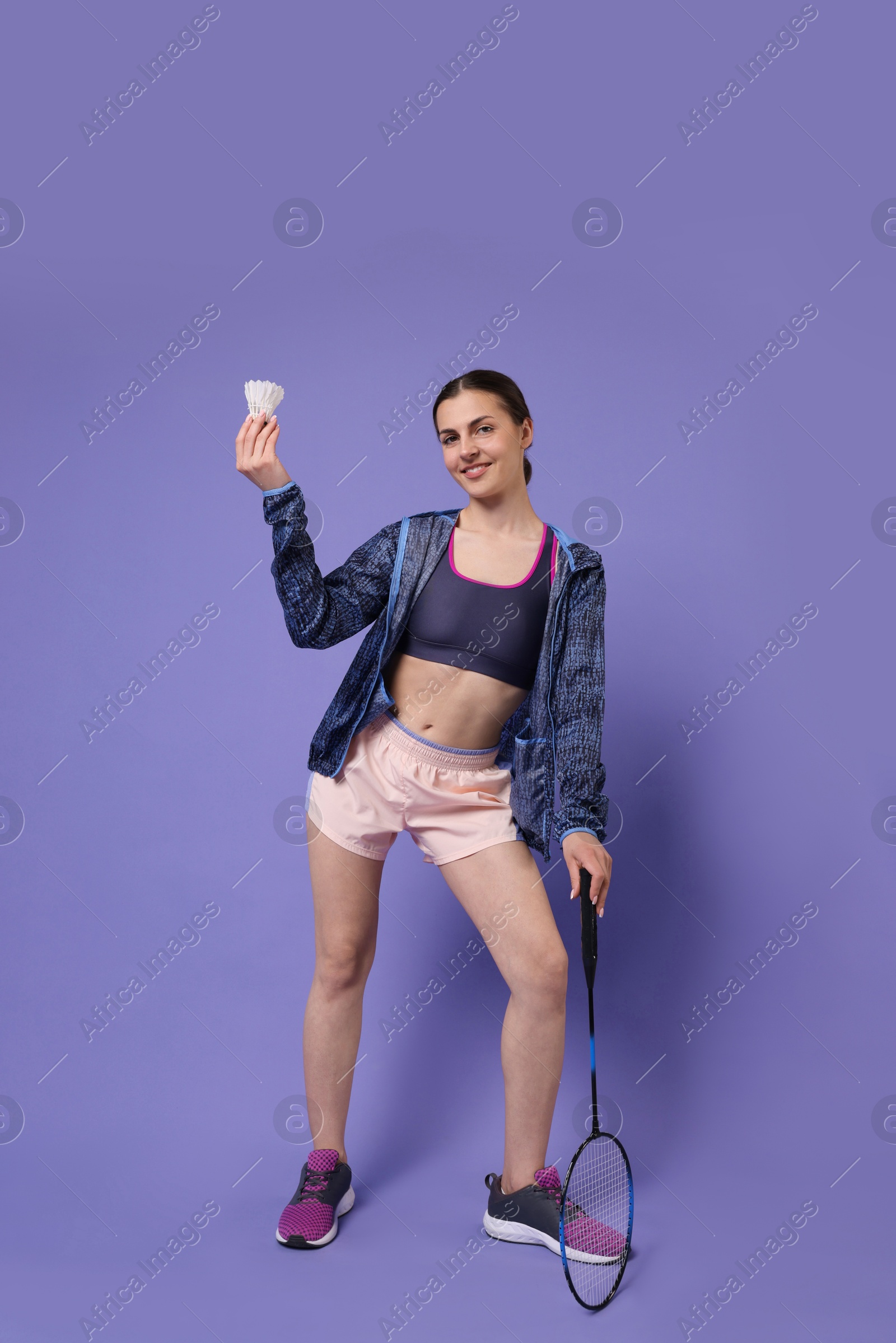 Photo of Young woman with badminton racket and shuttlecock on purple background