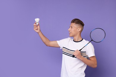 Photo of Young man with badminton racket and shuttlecock on purple background, space for text