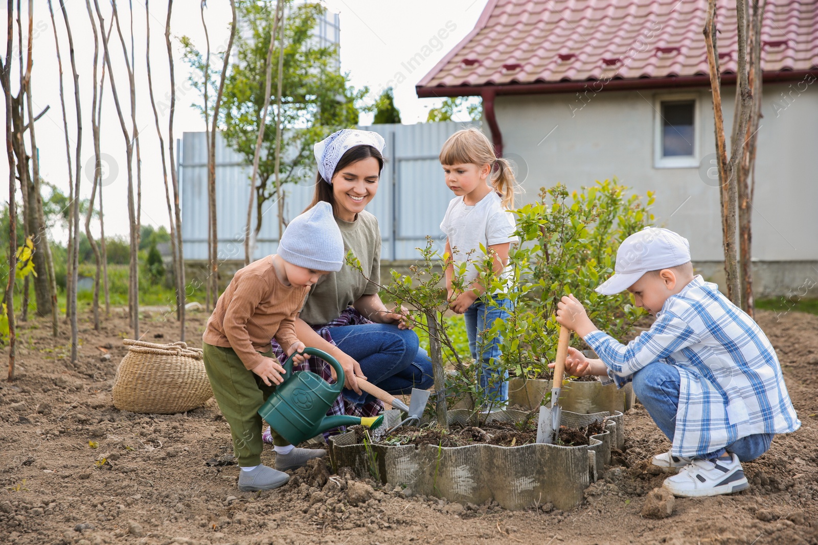 Photo of Mother and her children planting tree together in garden