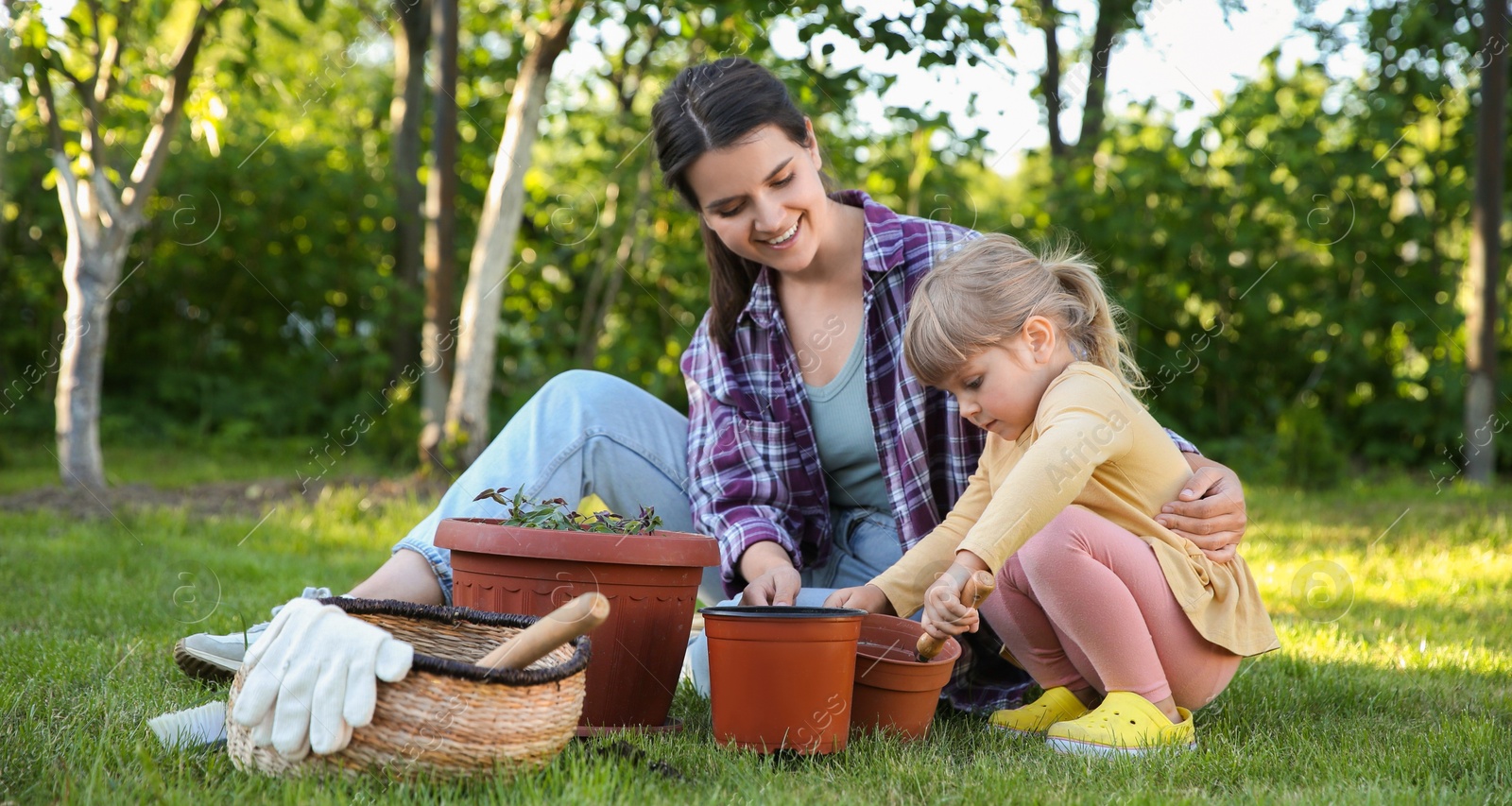 Photo of Mother and her daughter planting tree together in garden