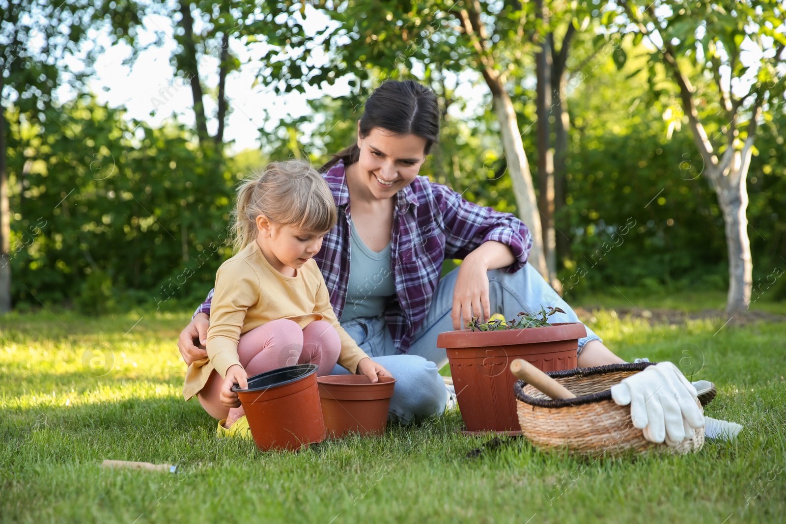 Photo of Mother and her daughter planting tree together in garden