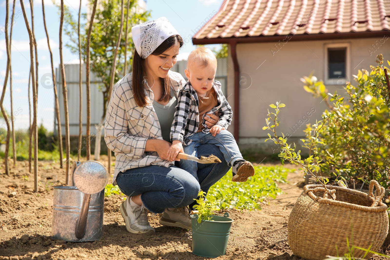 Photo of Mother and her cute son planting tree together in garden