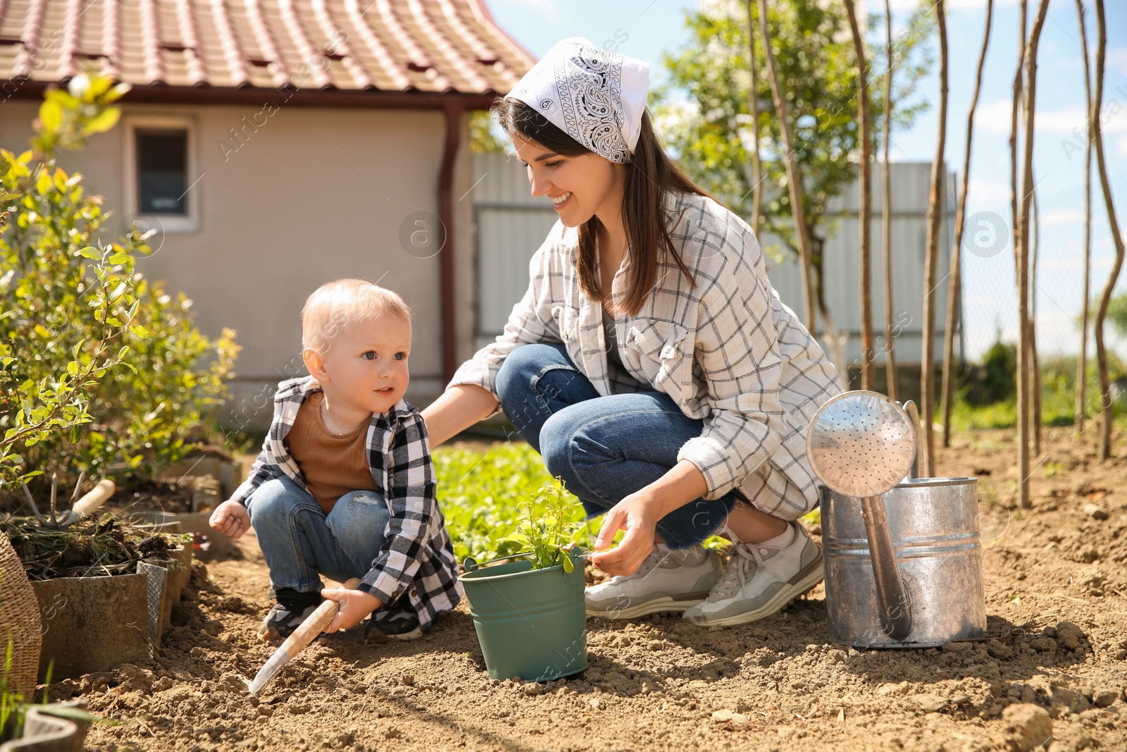 Photo of Mother and her cute son planting tree together in garden