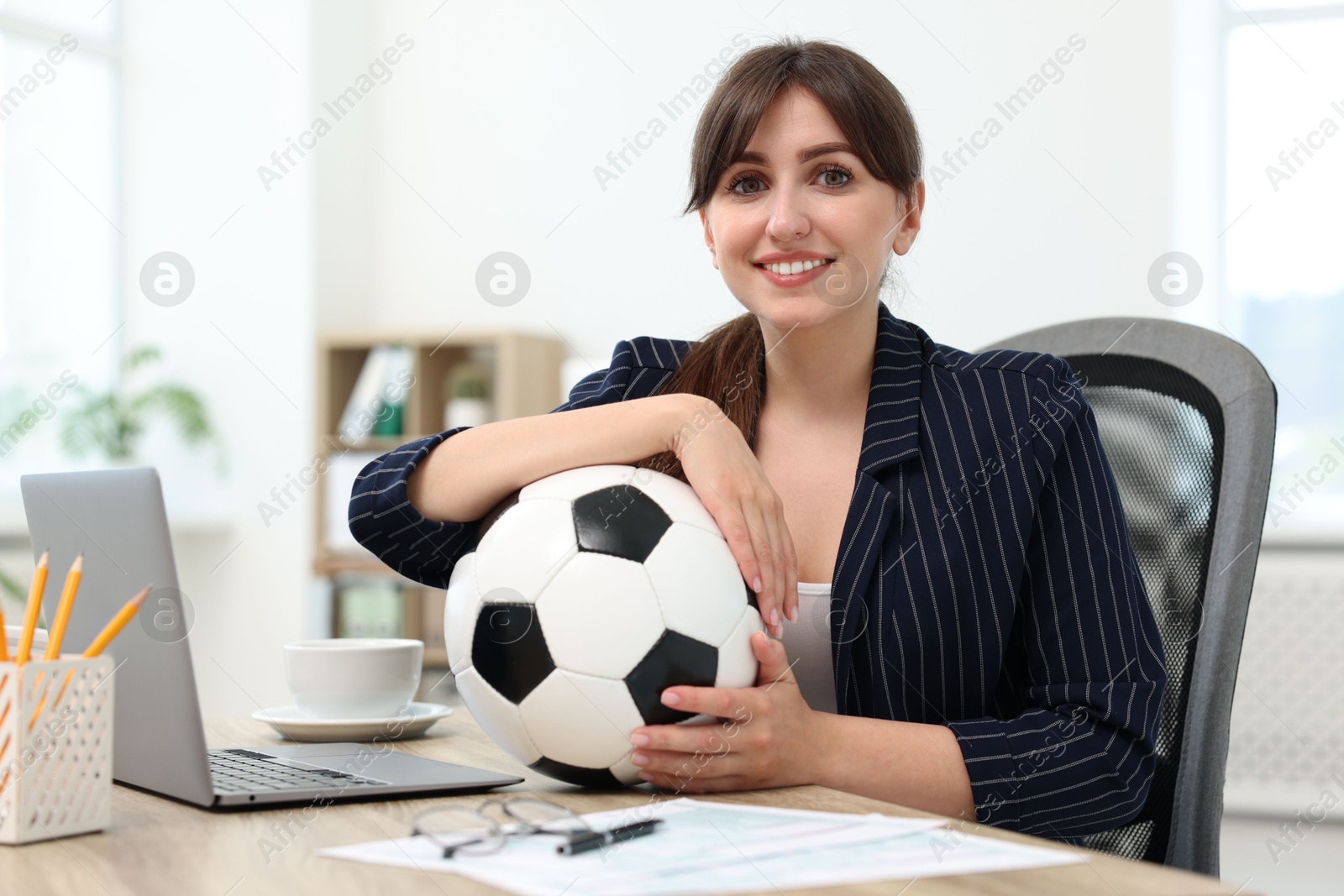 Photo of Smiling employee with soccer ball at table in office