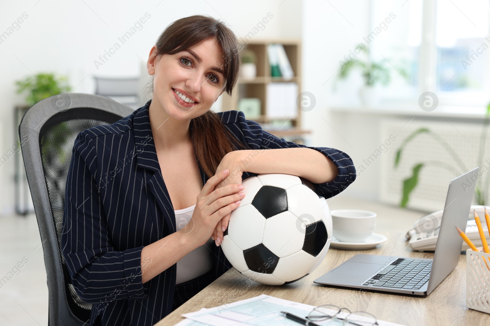 Photo of Smiling employee with soccer ball at table in office