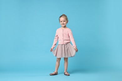 Cute little girl dancing on light blue background