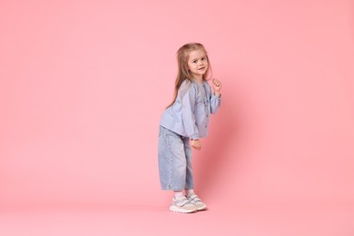 Cute little girl dancing on pink background