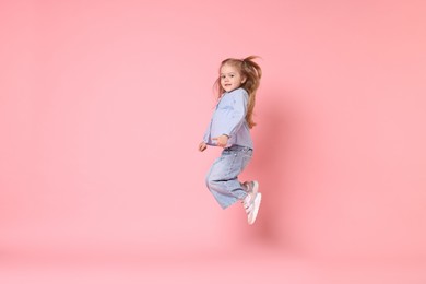 Cute little girl dancing on pink background, space for text