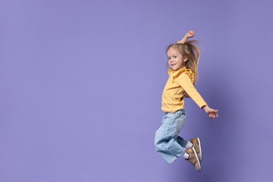 Photo of Cute little girl dancing on purple background, space for text