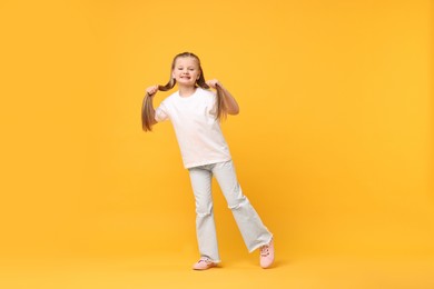 Cute little girl dancing on yellow background