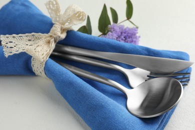 Stylish setting with cutlery and napkin on white textured table, closeup