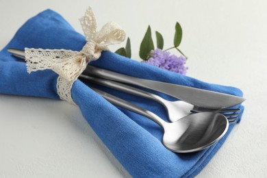 Photo of Stylish setting with cutlery and napkin on white textured table, closeup