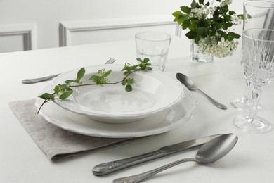 Photo of Stylish setting with cutlery and plates on white textured table