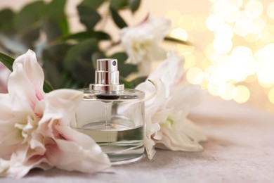 Photo of Bottle of perfume and beautiful lily flowers on table against beige background with blurred lights, closeup