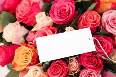 Photo of Bouquet of beautiful roses with blank card, closeup