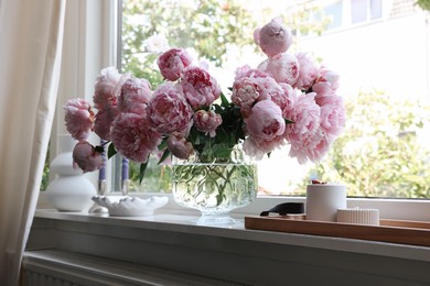 Photo of Beautiful pink peonies in vase on window sill. Interior design