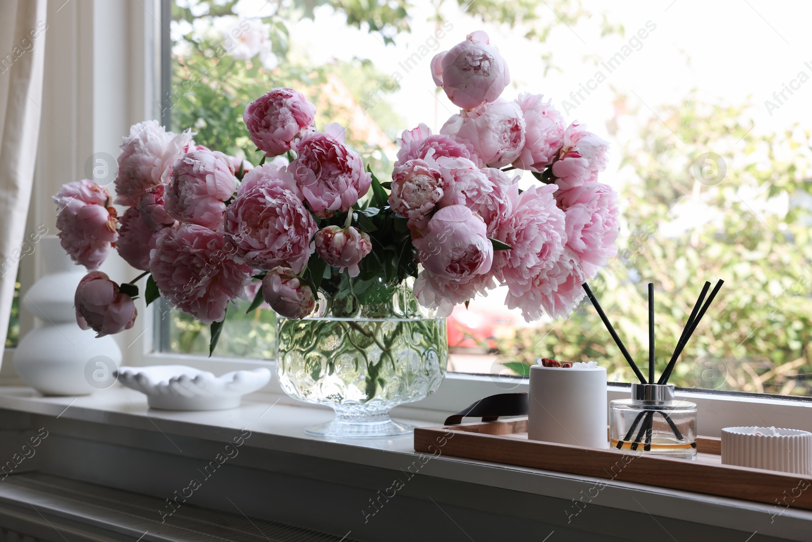 Photo of Beautiful pink peonies in vase on window sill. Interior design