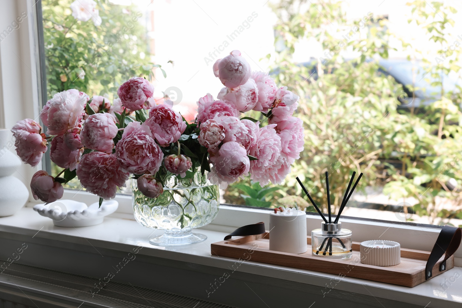 Photo of Beautiful pink peonies in vase on window sill. Interior design