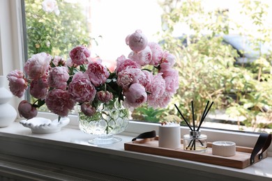 Beautiful pink peonies in vase on window sill. Interior design