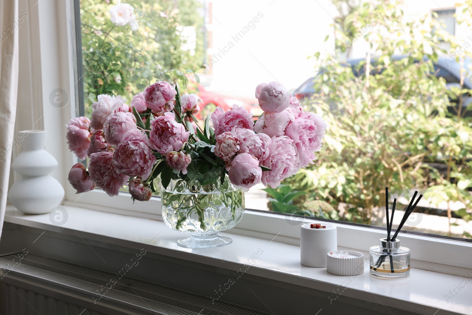 Photo of Beautiful pink peonies in vase on window sill. Interior design