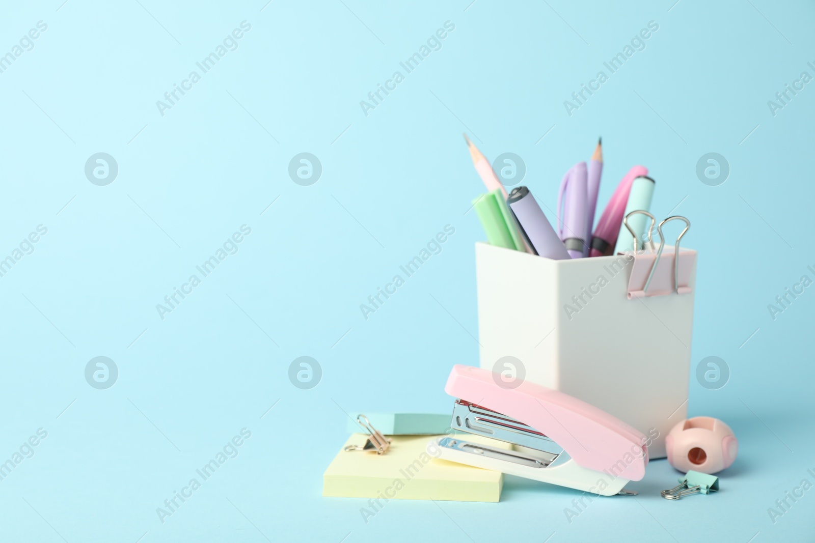 Photo of Stapler and other stationery on light blue background, space for text