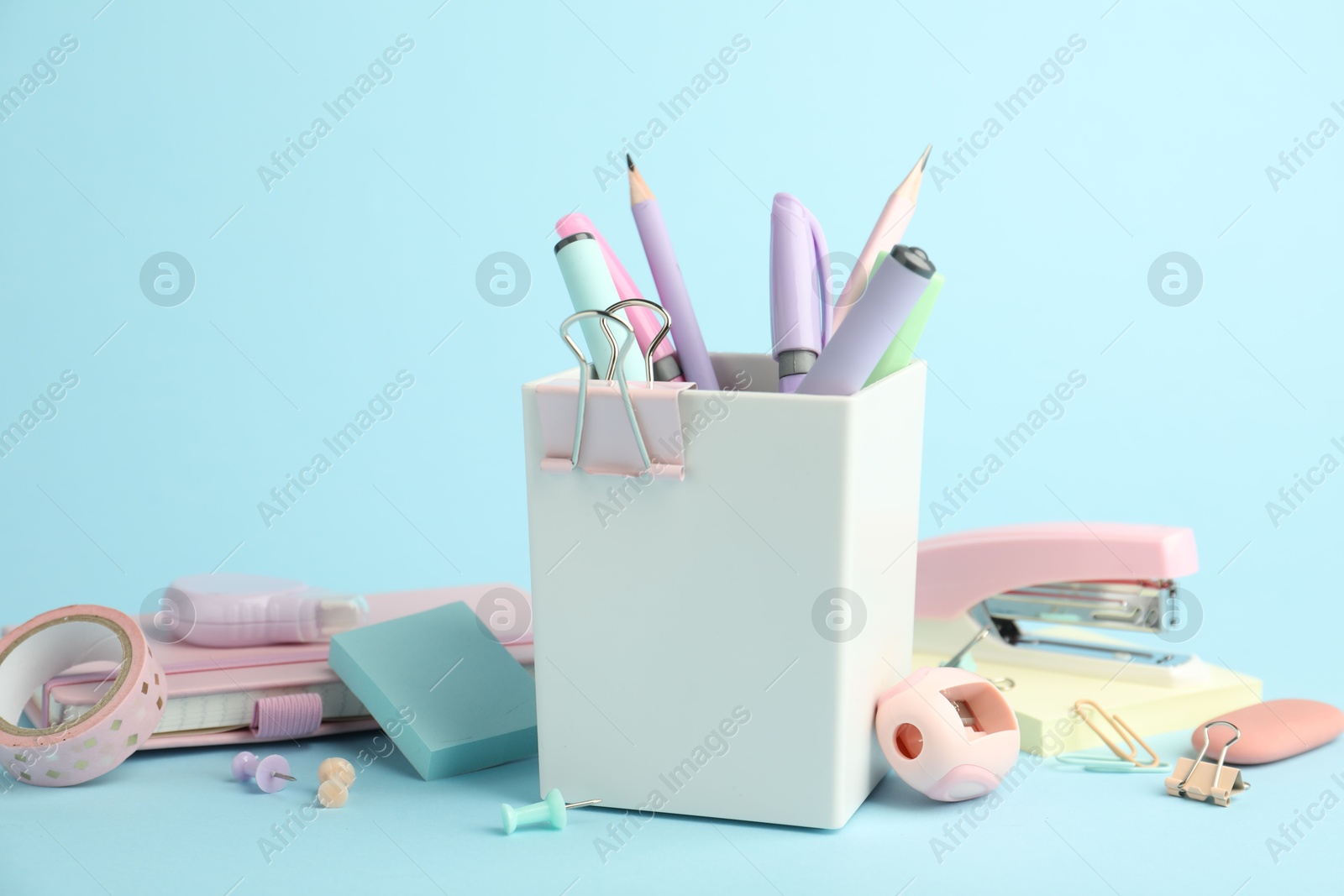 Photo of Stapler and other stationery on light blue background, closeup