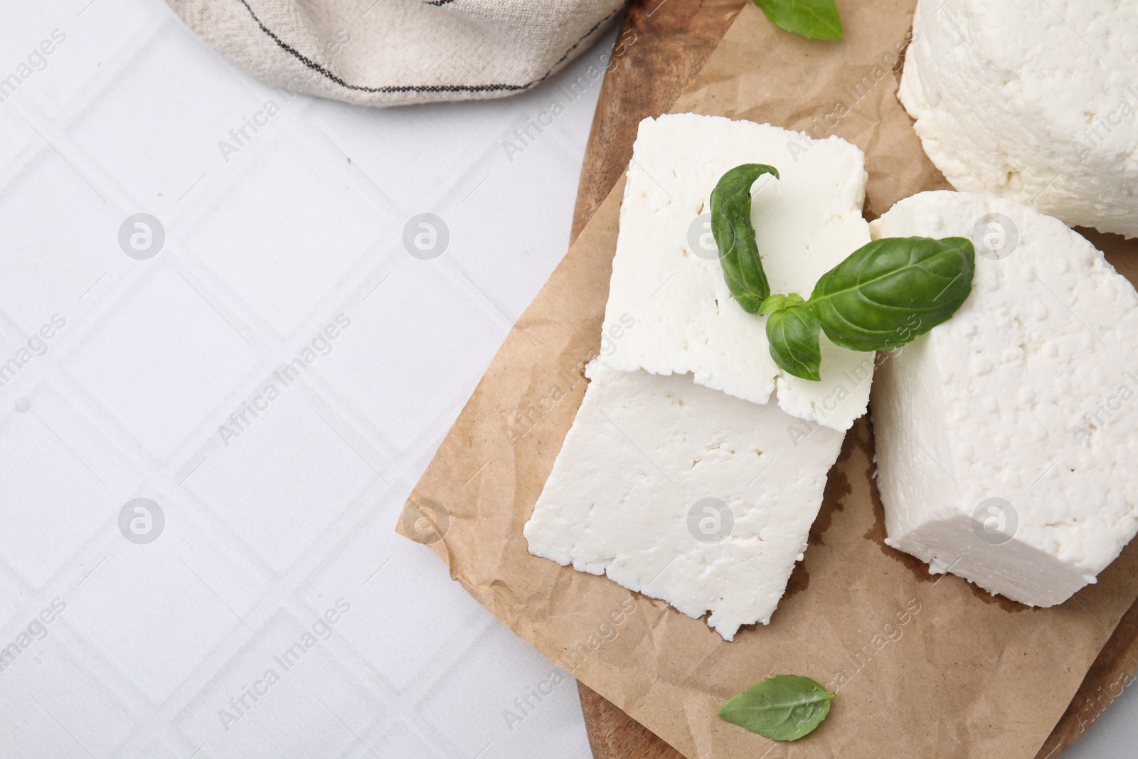 Photo of Fresh ricotta (cream cheese) and basil on white tiled table, flat lay. Space for text