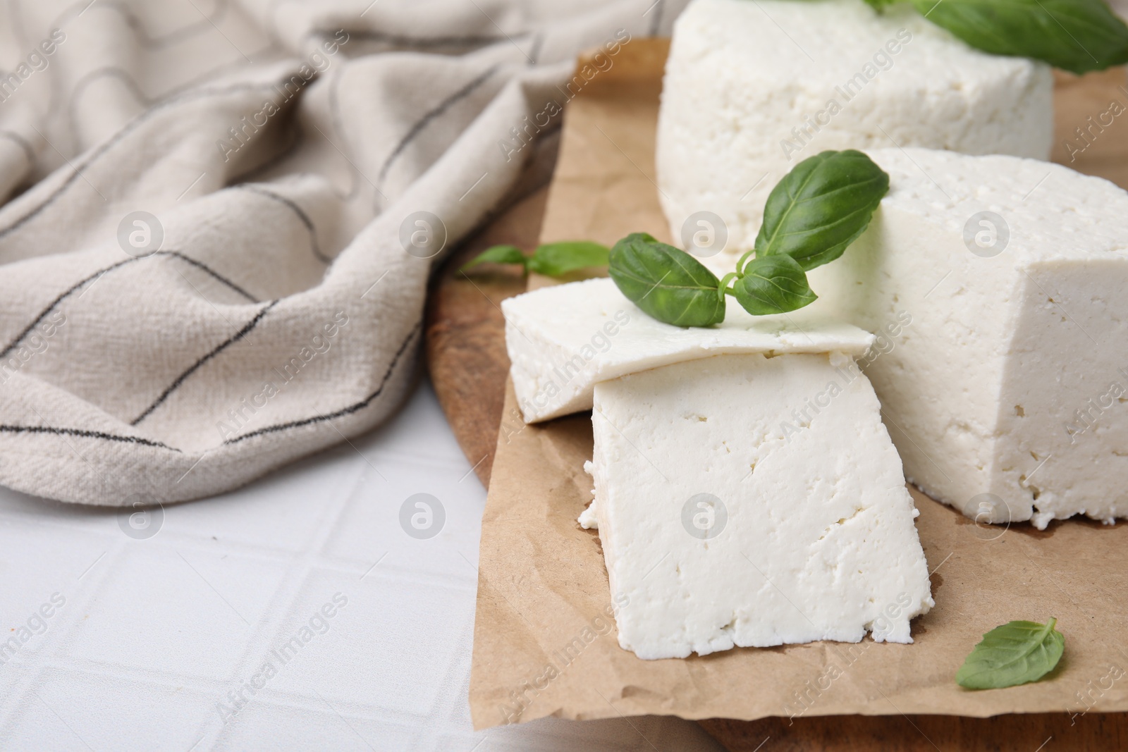 Photo of Fresh ricotta (cream cheese) and basil on white tiled table, closeup