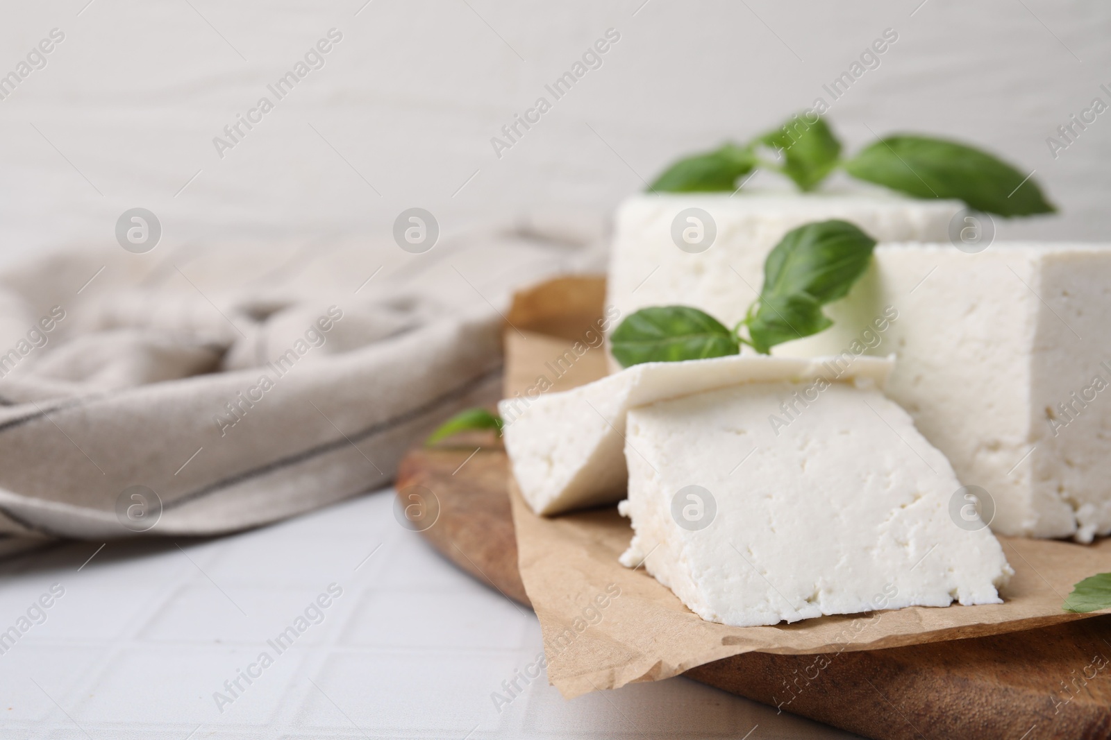 Photo of Fresh ricotta (cream cheese) and basil on white tiled table, closeup. Space for text