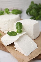 Photo of Fresh ricotta (cream cheese) and basil on white table, closeup