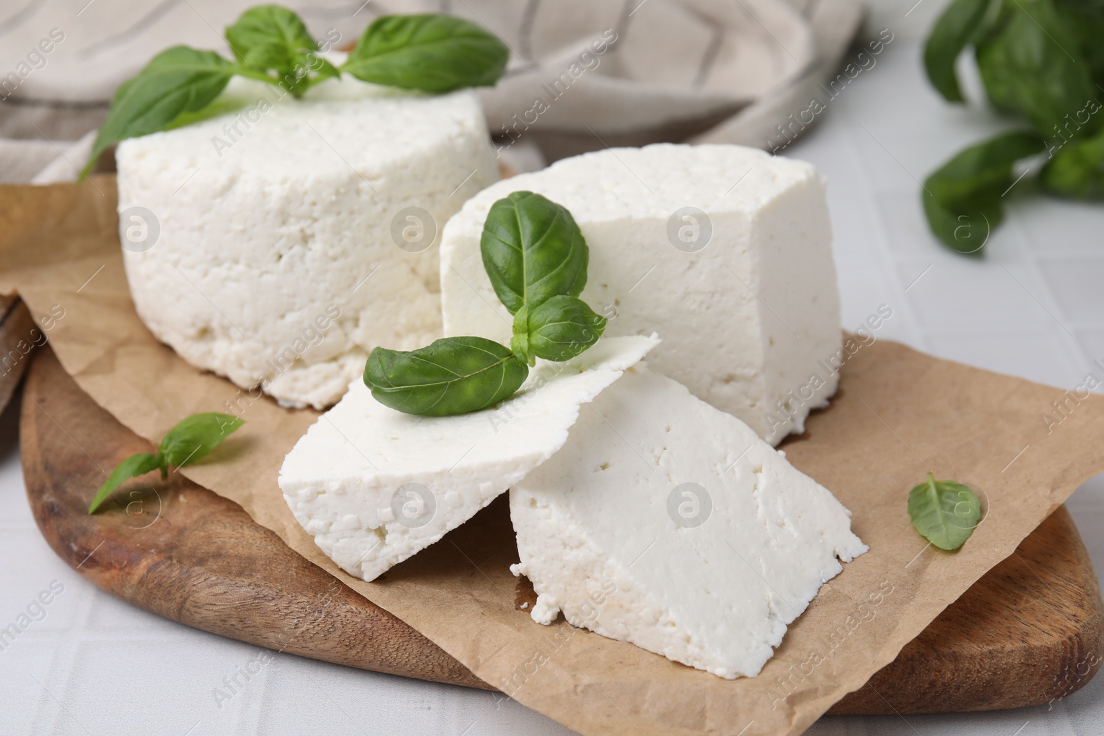 Photo of Fresh ricotta (cream cheese) and basil on white tiled table, closeup