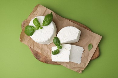 Fresh ricotta (cream cheese) and basil on green table, top view