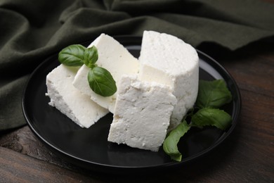 Photo of Fresh ricotta (cream cheese) and basil on wooden table, closeup