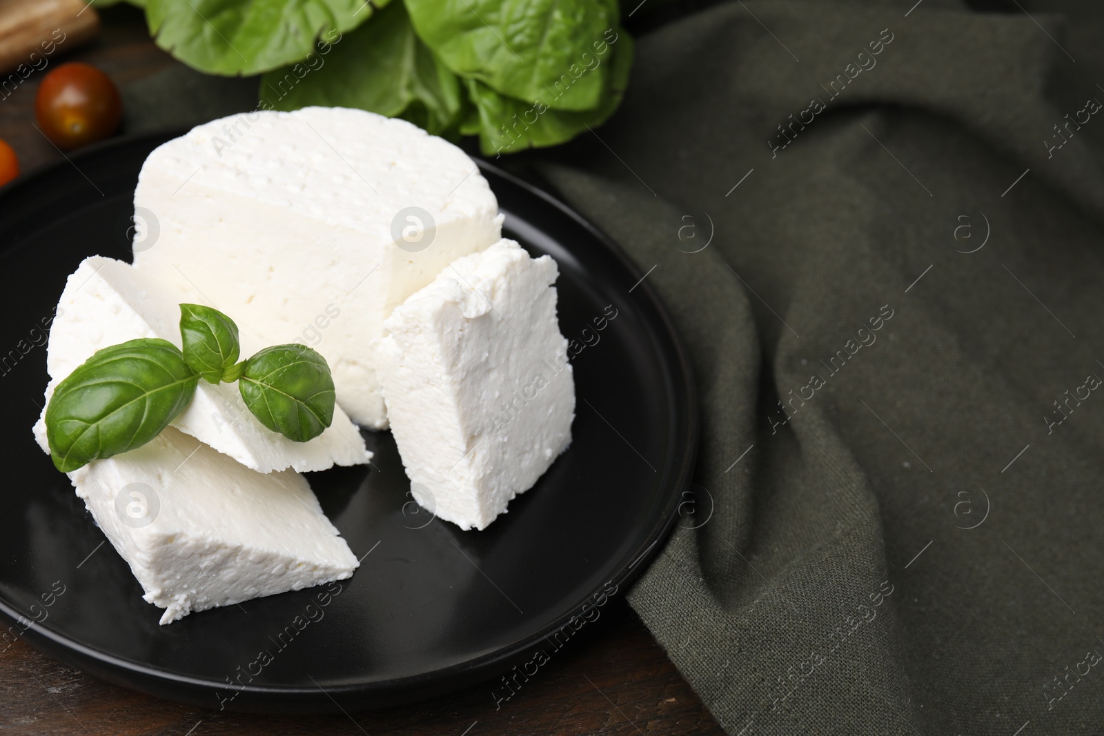 Photo of Fresh ricotta (cream cheese) and basil on table, closeup. Space for text