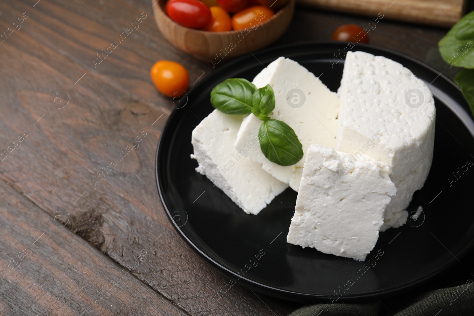 Photo of Fresh ricotta (cream cheese) and basil on wooden table, closeup. Space for text