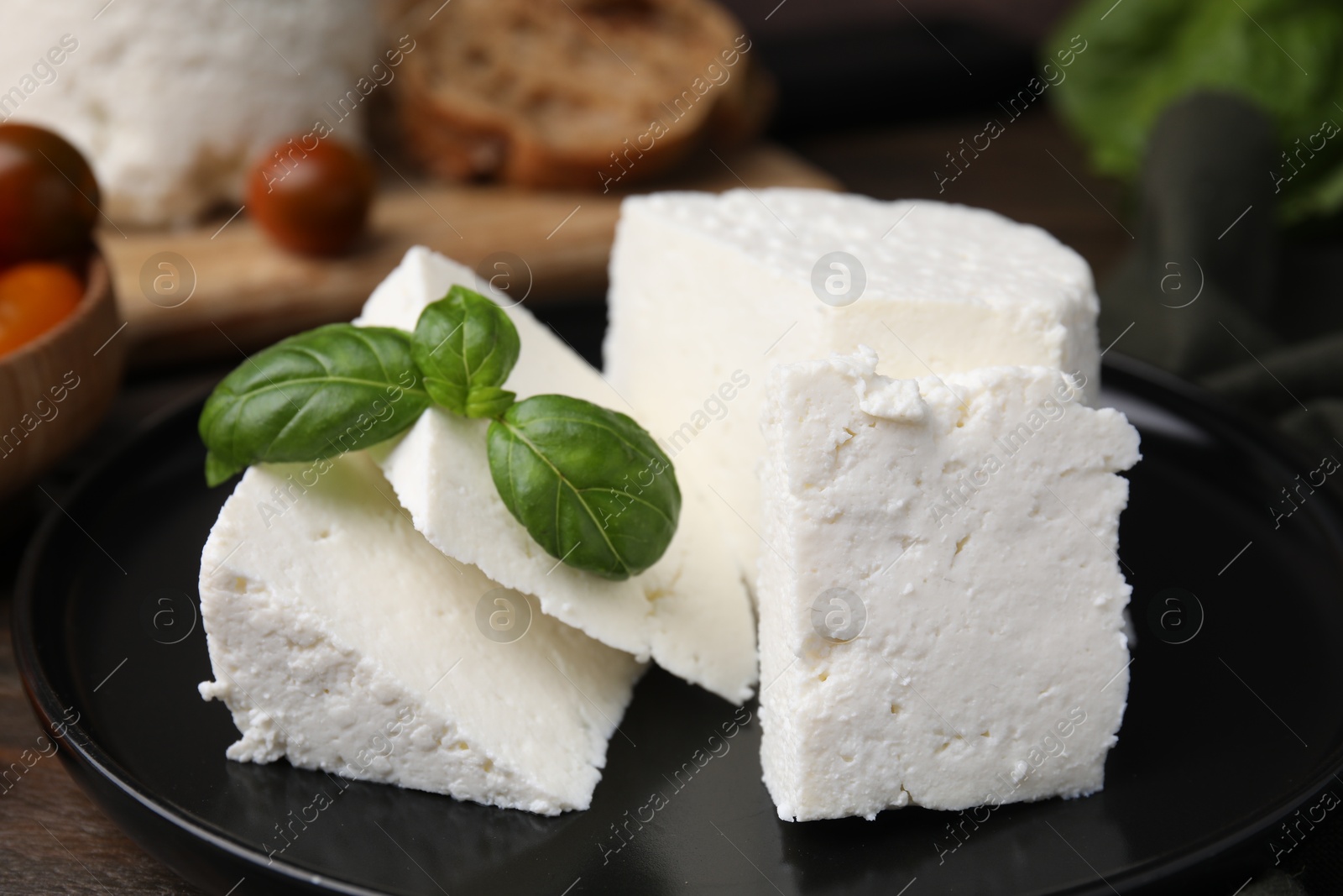 Photo of Fresh ricotta (cream cheese) and basil on table, closeup