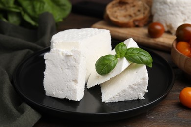 Photo of Fresh ricotta (cream cheese) and basil on wooden table, closeup